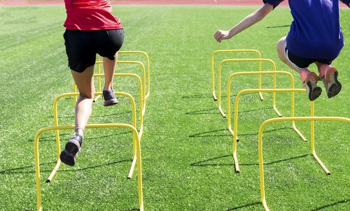 athletes jump over hurdles